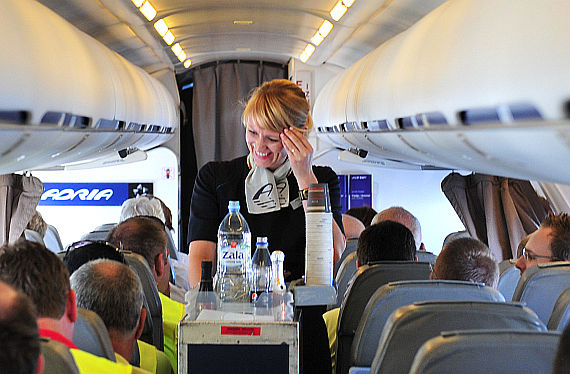 Flugbegleiterin an Bord eines Adria Airways CRJ900 bei der Arbeit