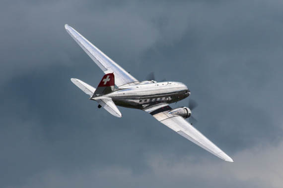 Die Sonne glitzerte am silbernen Rumpf der 1943 gebauten DC-3 von Hugo Mathys, im Hintergrund die dunklen Wolken des aufziehenden Regenschauers - Foto: Jakob Rettenwender