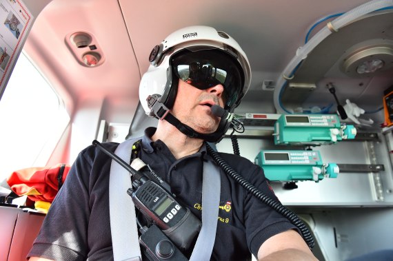 Der Notarzt steht mit den übrigen Crewmitglieder in Sprechverbindung. Im Hintergrund ist ein Teil der medizinischen Notfallausrüstung des Helikopters zu erkennen.
