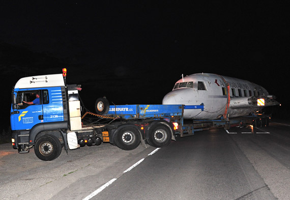 Der von mehreren Begleitfahrzeugen eskortierte Tieflader fährt von der B 17 aus zum Flugplatzgelände zu - Foto: Austrian Wings Media Crew